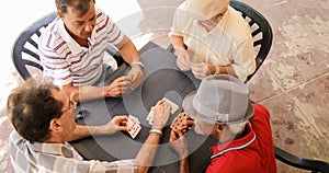 Group Of Senior Men Playing Cards Game In Patio