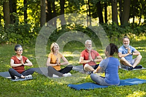 Group of senior people attending yoga class with instructor outdoors