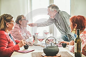 Group of senior people drinking italian style moka coffee and tea after lunch - Mature happy friends eating biscuits and laughing