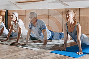 group of senior people practicing yoga in dog pose on mats