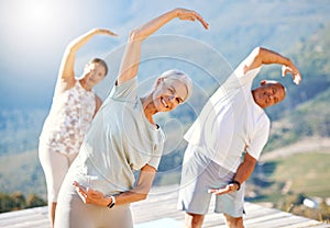 Group of senior people stretching with their hands over heads outdoors. Happy mature people doing yoga exercise in