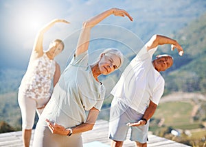 Group of senior people stretching with their hands over heads outdoors. Mature people doing yoga exercise in nature on a