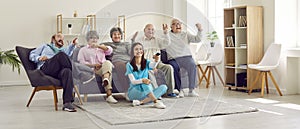 Group of senior people watching TV in retirement home together with young nurse.