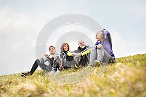 Skupina starších bežcov vonku, odpočíva a rozpráva sa.