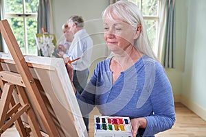 Group Of Seniors Attending Painting Class With Teacher