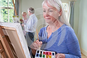 Group Of Seniors Attending Painting Class With Teacher