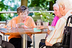 Group of seniors playing board game on terrace of retirement home