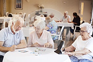 Group Of Seniors Playing Game Of Bingo In Retirement Home