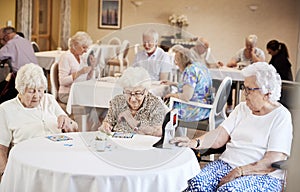 Group Of Seniors Playing Game Of Bingo In Retirement Home