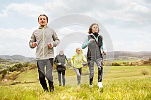 Group of seniors running outside on green hills.