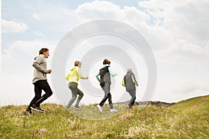 Group of seniors running outside on the green hills.