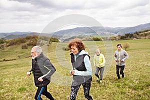 Group of seniors running outside on the green hills.