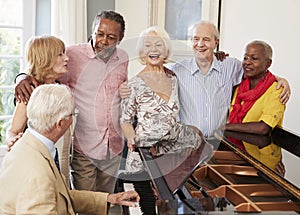 Group Of Seniors Standing By Piano And Singing Together