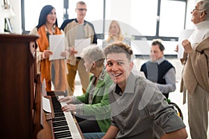 Group of seniors with young teacher singing together at choir rehearsal. photo