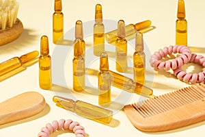 Group, set Cosmetic ampoules with serum for hair growth, restoration. Hair comb, Spiral Hair Ties on a beige background. Concept