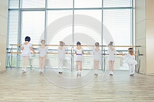 Group of seven little ballerinas standing in row and practicing
