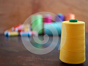 Group of sewing threads in many colors on a dark table with big cone in yellow