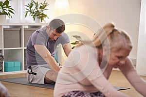 Group Sitting On Exercise Mats Stretching In Yoga Class Inside Community Center