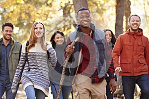 Group of six friends hiking together through a forest