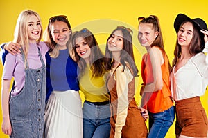Group of six laughing girls having party summer style yellow background studio