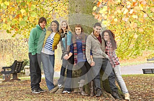 Group Of Six Teenage Friends Leaning Against Tree