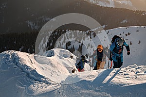 group of skiers in bright ski suits climbing up at snow-covered mountain trail