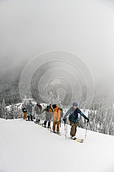 Group of skiers hiking on skis in snow up to the top of a snowy mountain slope. Skitour concept.