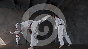 A group of skilled athletes in white kimonos synchronously performs a set of taekwondo leg kick exercises. The combat