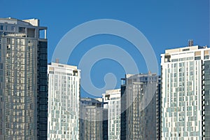 Group of skyscrapers or flat block buildings on clear blue sky background. Closeup view with copy space. Modern urban architecture