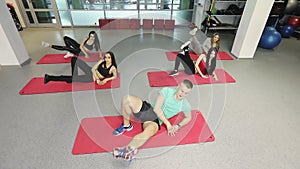 A group of slender girls with fitness instructor works with a coach in a fitness gym.