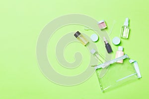 Group of small bottles for travelling on green background. Copy space for your ideas. Flat lay composition of cosmetic products.