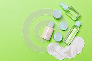 Group of small bottles for travelling on green background. Copy space for your ideas. Flat lay composition of cosmetic products.