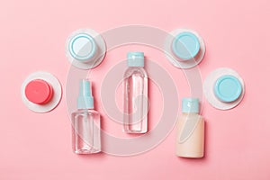 Group of small bottles for travelling on pink background. Copy space for your ideas. Flat lay composition of cosmetic products.