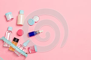 Group of small bottles for travelling on pink background. Copy space for your ideas. Flat lay composition of cosmetic products.