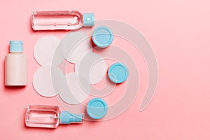 Group of small bottles for travelling on pink background. Copy space for your ideas. Flat lay composition of cosmetic products.