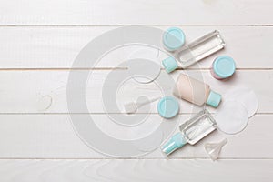 Group of small bottles for travelling on wooden background. Copy space for your ideas. Flat lay composition of cosmetic products.