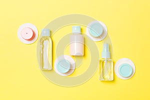 Group of small bottles for travelling on yellow background. Copy space for your ideas. Flat lay composition of cosmetic products.