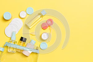 Group of small bottles for travelling on yellow background. Copy space for your ideas. Flat lay composition of cosmetic products.