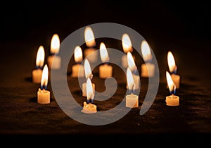 A group of small, lit candles arranged in a scattered pattern on a