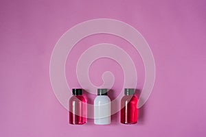 Group of small travel bottles for body care: shower gel, shampoo, balm, lotion on pink background. The composition of the flat lay