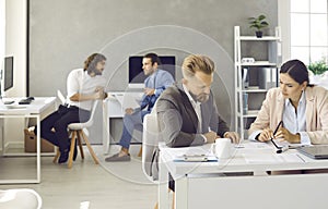 Group of smart successful business people working and communicating together in coworking office.