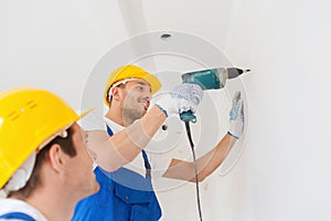 Group of smiling builders with drill indoors