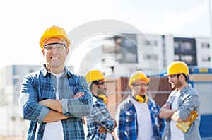 Group of smiling builders in hardhats outdoors