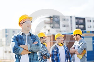 Group of smiling builders in hardhats outdoors