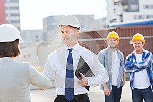 Group of smiling builders in hardhats outdoors