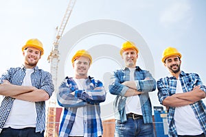 Group of smiling builders in hardhats outdoors