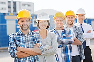 Group of smiling builders in hardhats outdoors