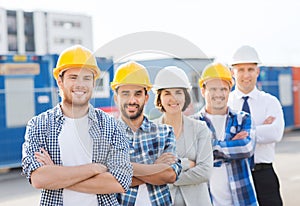 Group of smiling builders in hardhats outdoors