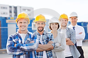 Group of smiling builders in hardhats outdoors