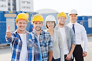 Group of smiling builders in hardhats outdoors